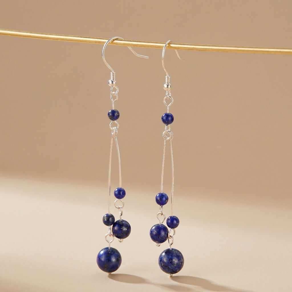 Boucles d'oreilles longues en argent avec des perles de lapis-lazuli bleues de différentes tailles, suspendues à des fils fins. @main