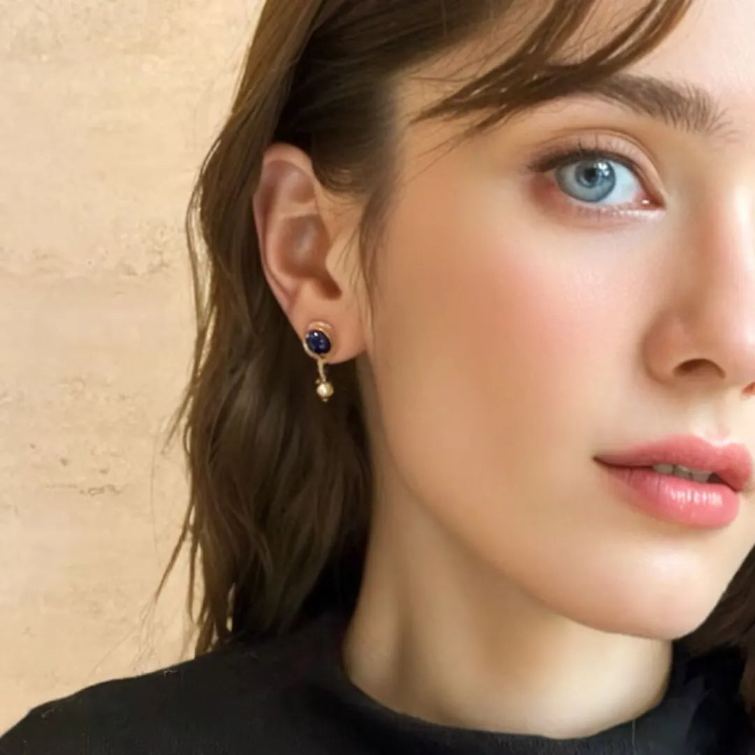 Boucles d'oreilles pendantes en argent doré ornées d'un cabochon de lapis lazuli bleu profond et d'une petite perle nacrée, inspirées par le motif serpent.