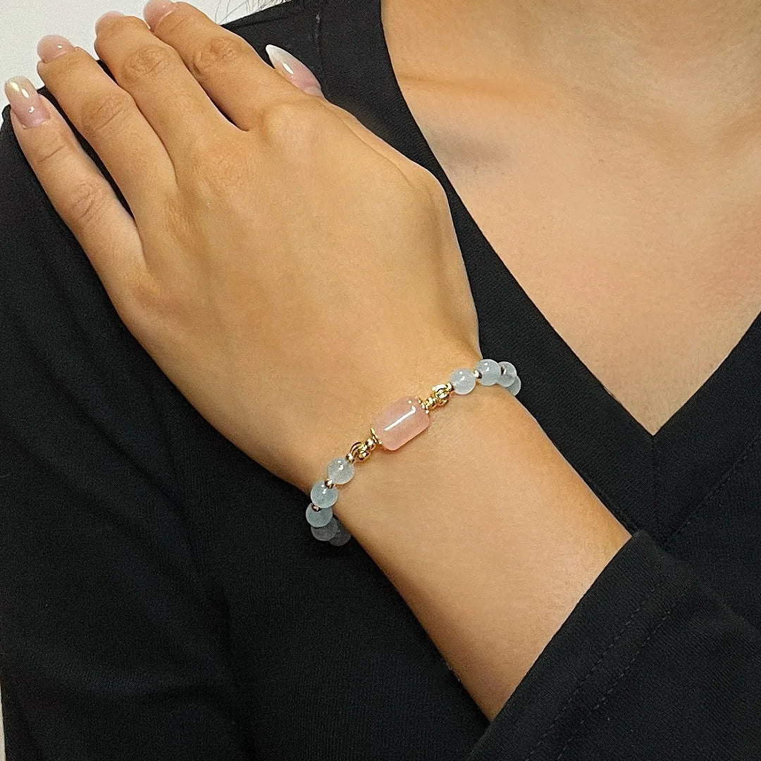 Bracelet "Souffle Doux" en aigue-marine et quartz rose, orné de perles dorées délicates. Gros plan porté au poignet.