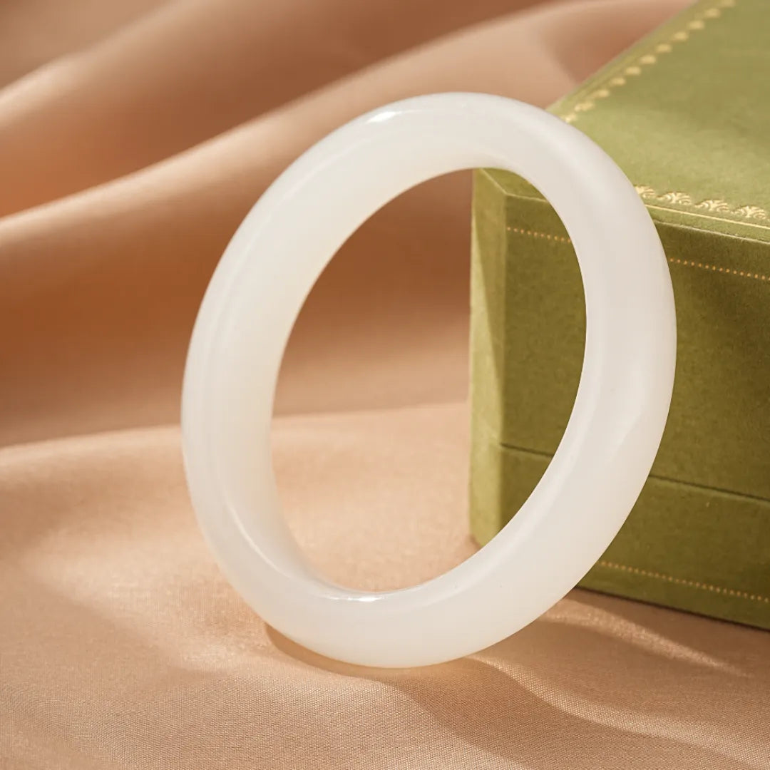 Bracelet jonc en jade blanc, nommé "Paix Intérieure", présenté sur un fond satiné avec une boîte cadeau verte.
