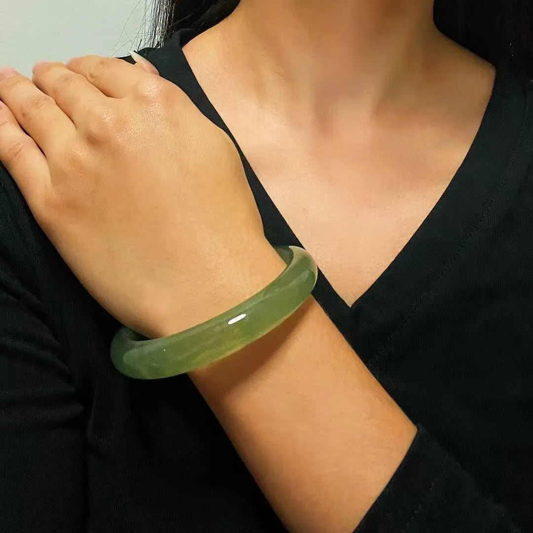 Bracelet jonc en jade vert pâle "Puissance Tranquille" porté au poignet d'une femme