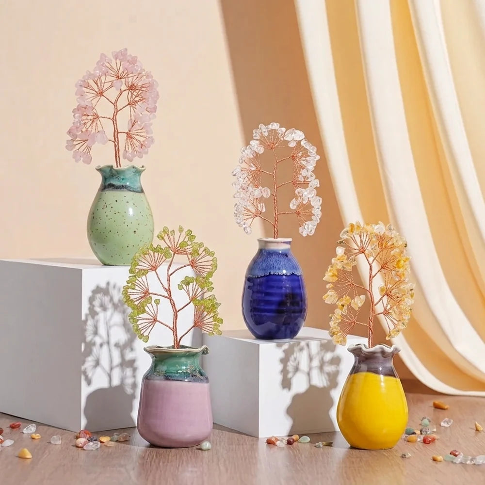 Quatre arbres de vie décoratifs en pierres naturelles (rose, blanc, vert et jaune) dans des vases colorés, disposés sur des podiums blancs.