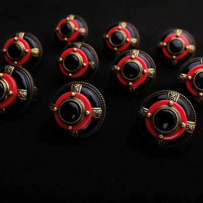 Plusieurs bagues "Merveille d'Antan" avec une agate noire centrale, un anneau rouge et des détails dorés sur fond noir.