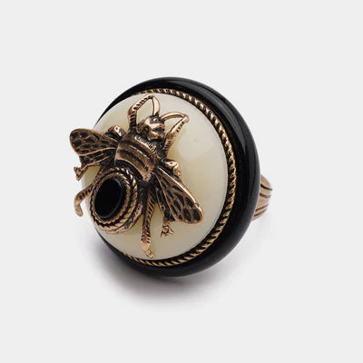 Bague Agate Noire "Reine Noire" avec un motif d'abeille en bronze sur un fond crème et un contour noir.