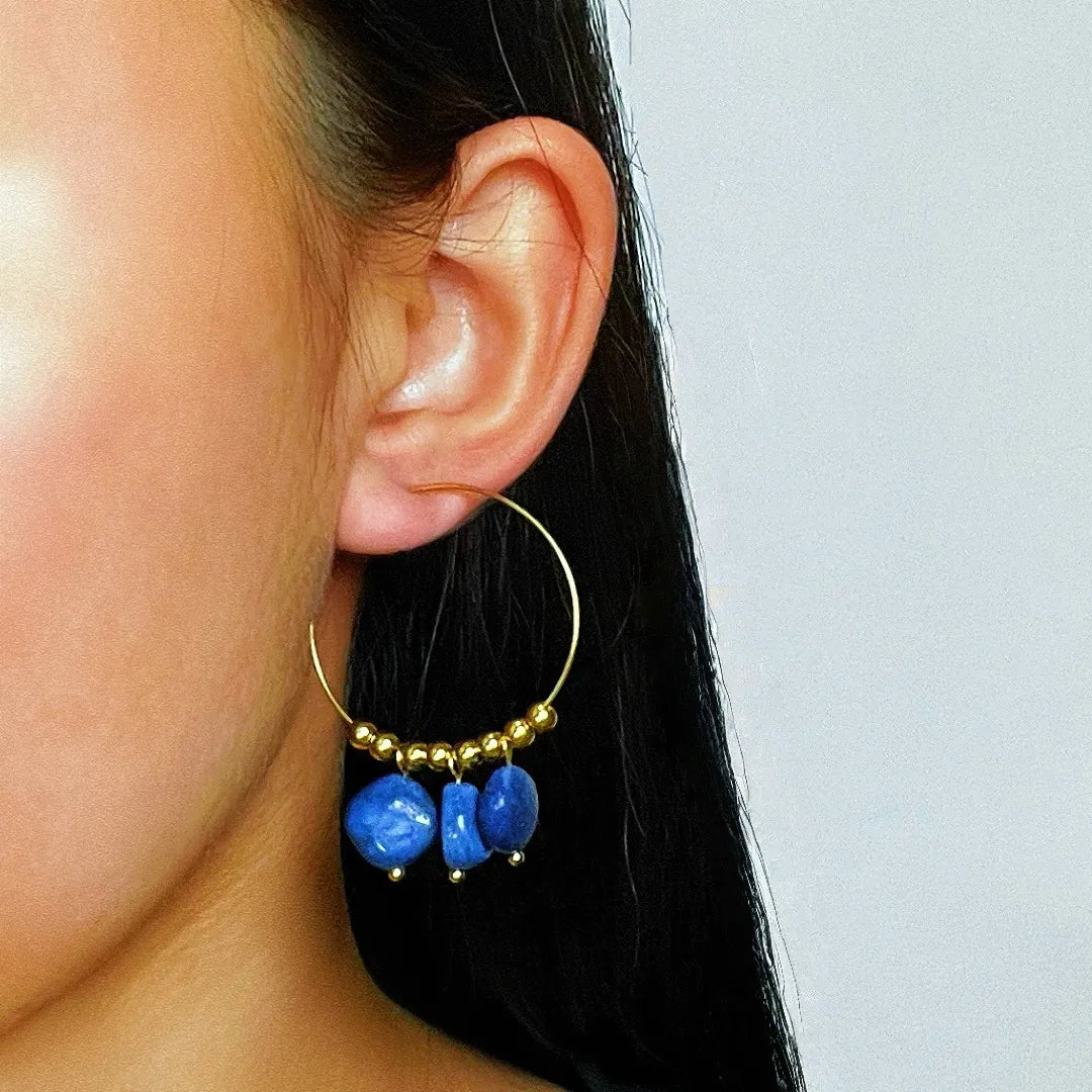 Boucles d'oreilles créoles dorées ornées de perles dorées et de trois pierres bleues naturelles, type amazonite ou lapis lazuli, suspendues.