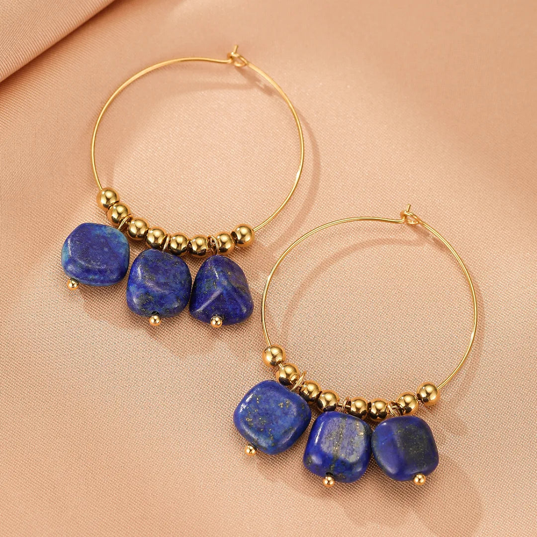 Paire de boucles d'oreilles créoles dorées ornées de pierres bleues naturelles en lapis-lazuli cubiques et de petites perles dorées.