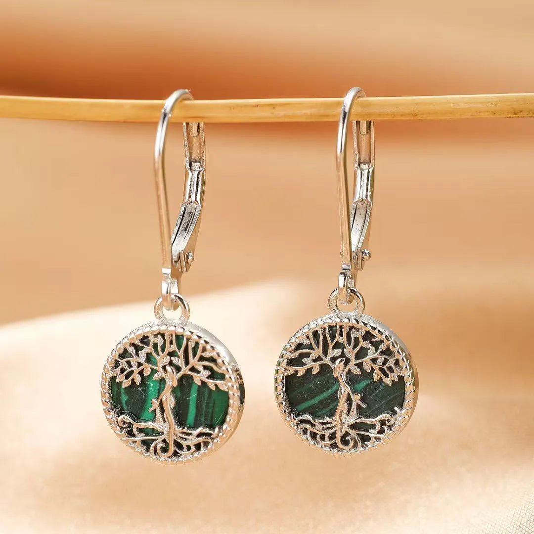 Boucles d'oreilles argentées avec un motif d'arbre de vie ajouré encadrant une pierre de malachite verte striée. Style pendant avec fermoir crochet.