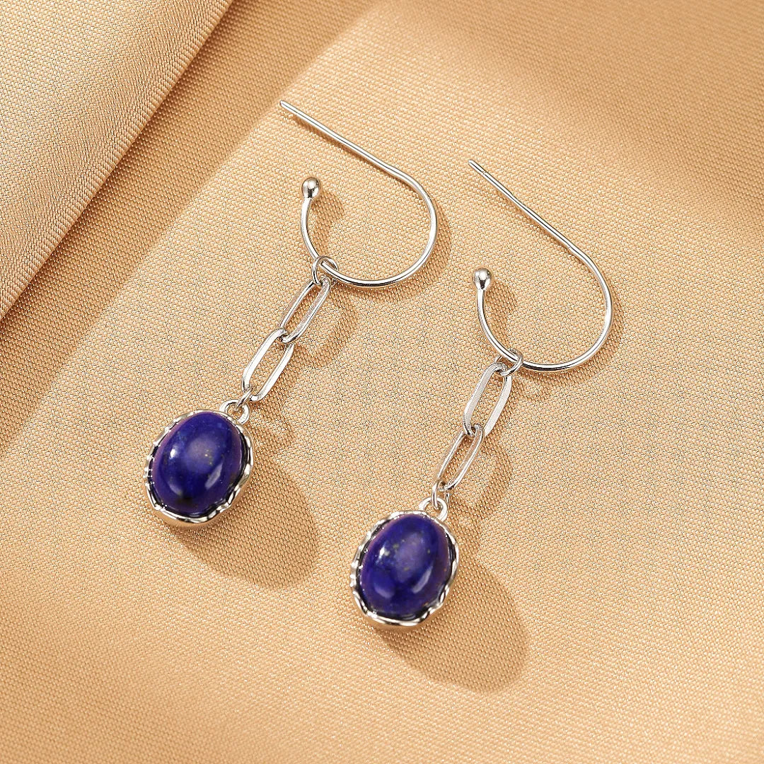 Boucles d'oreilles élégantes en argent 925 avec pendentifs ovales en lapis-lazuli bleu profond, ornées de détails travaillés et d'une chaîne gourmette fine.