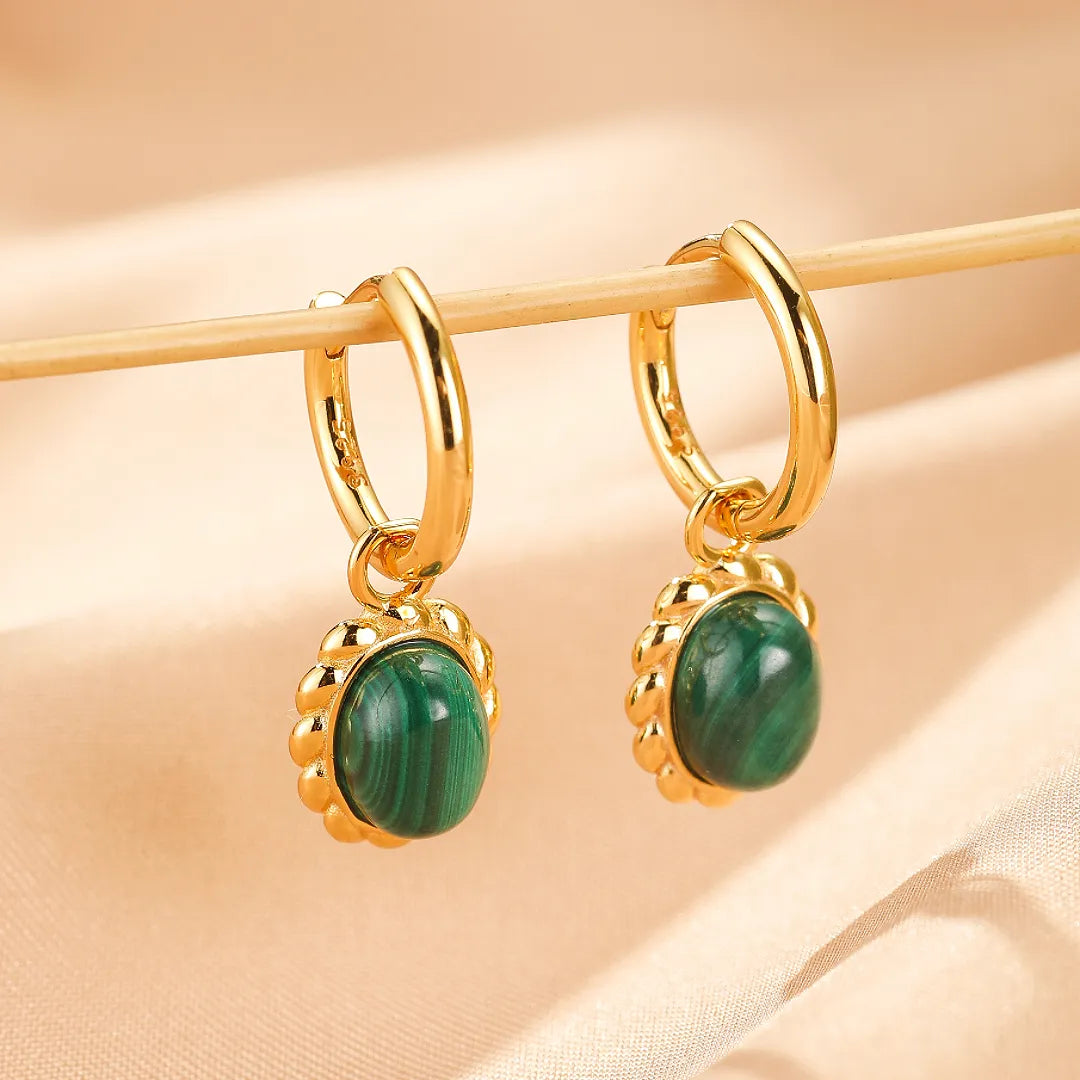 Boucles d'oreilles pendantes en argent doré ornées de pierres de malachite facettées, suspendues à des anneaux.