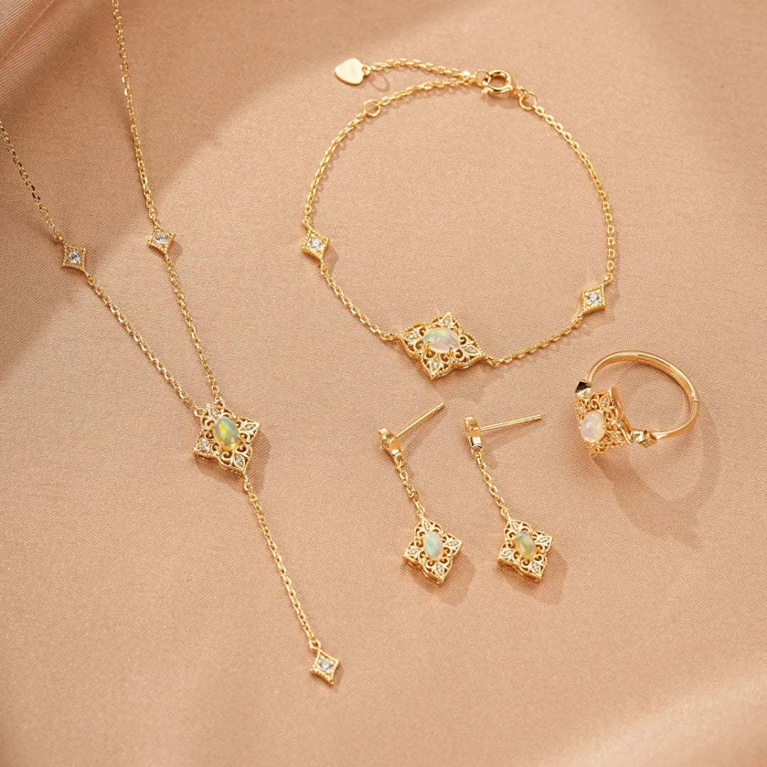 Ensemble de bijoux en argent doré 10K comprenant un collier, un bracelet, une bague et des boucles d'oreilles ornés d'opales et de diamants dans un design complexe.