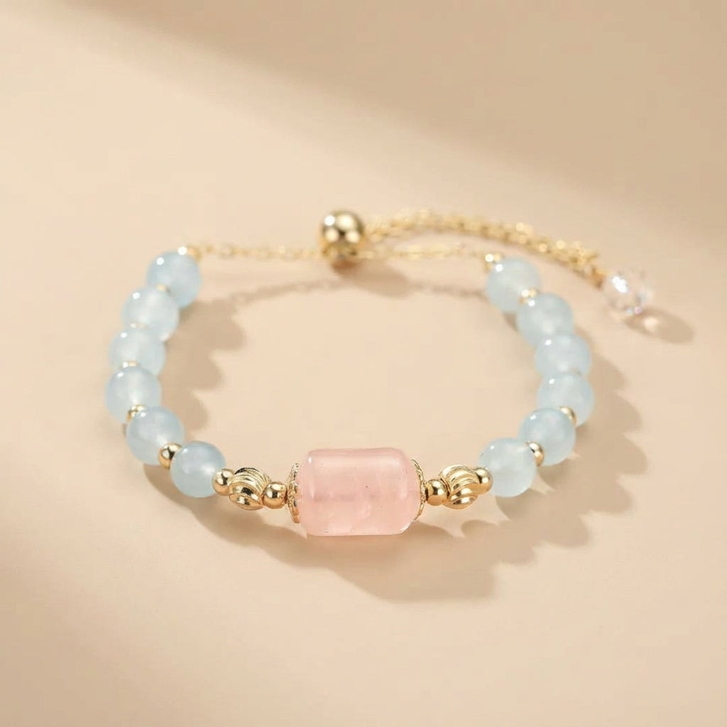Bracelet "Souffle Doux" en aigue-marine et quartz rose, avec des perles bleues claires et une pierre rose centrale, monté sur une chaîne dorée réglable.