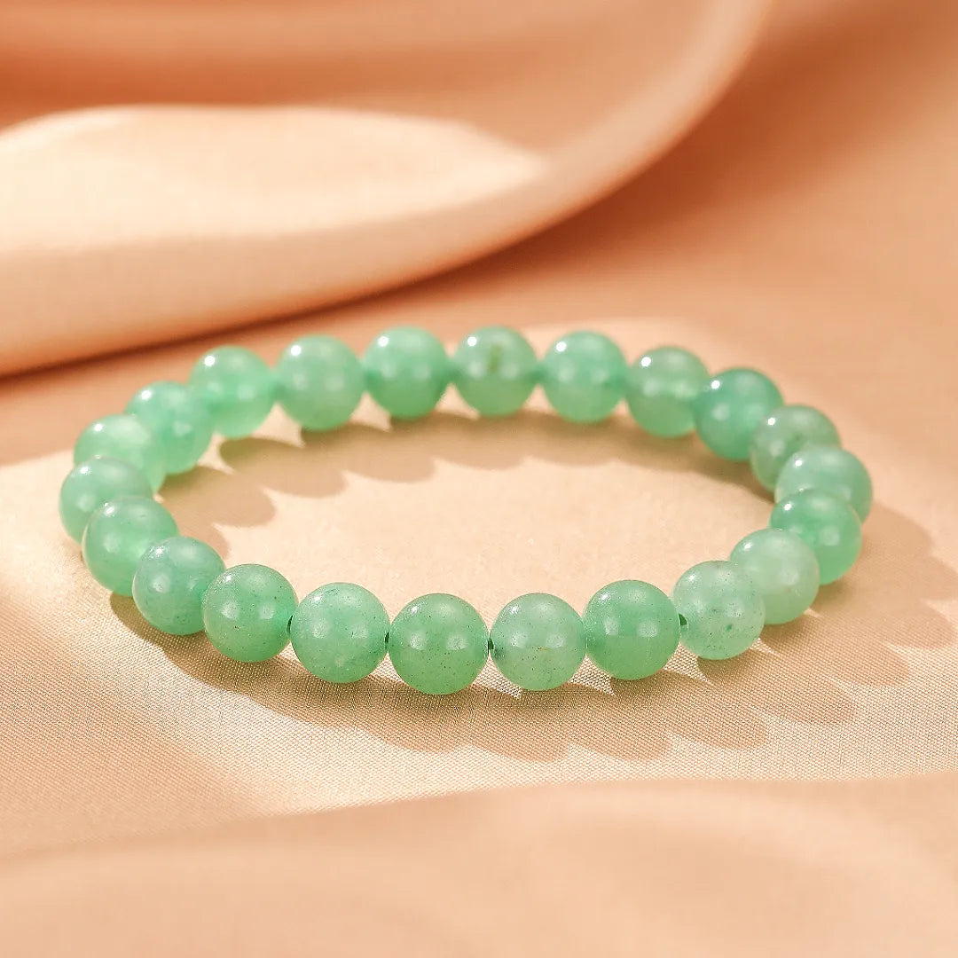 Bracelet en aventurine verte "Énergie Douce" composé de perles rondes polies sur fond satiné rose pâle.