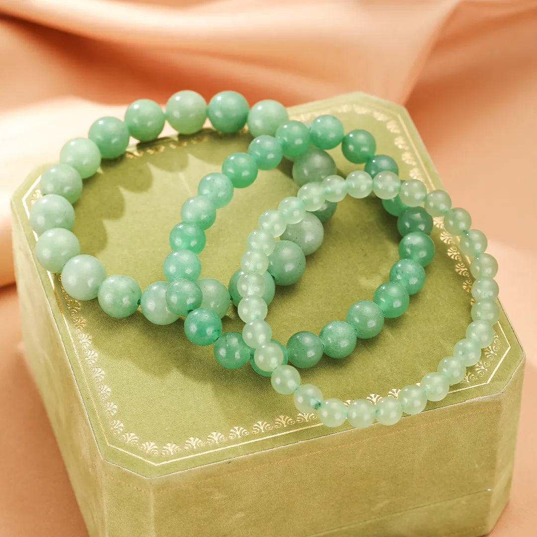 Trois bracelets en aventurine verte, nommés "Énergie Douce", sur une boîte cadeau verte.
