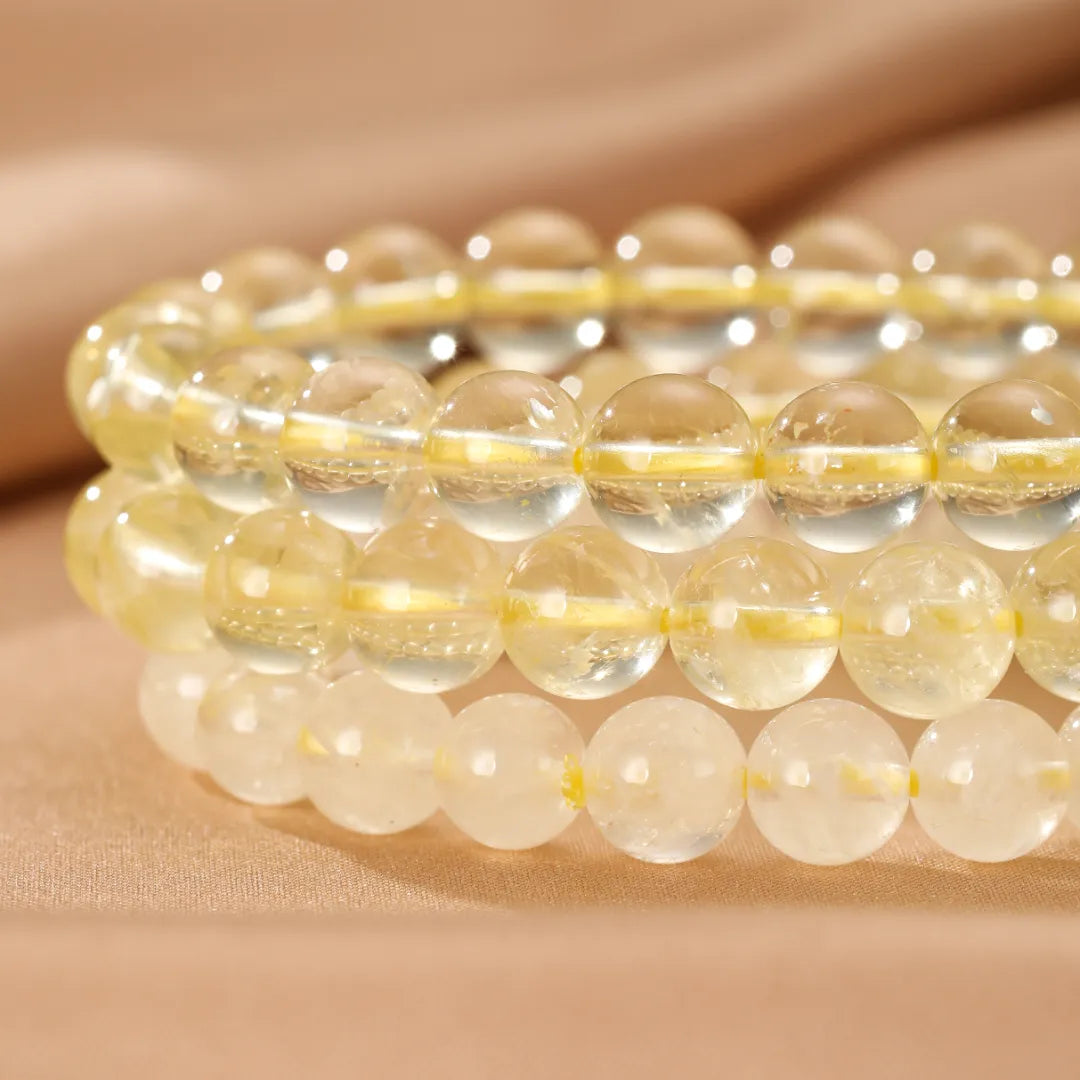 Bracelet Citrine "Lumière Intérieure" composé de perles rondes transparentes et jaunes sur un fond beige satiné doux et texturé