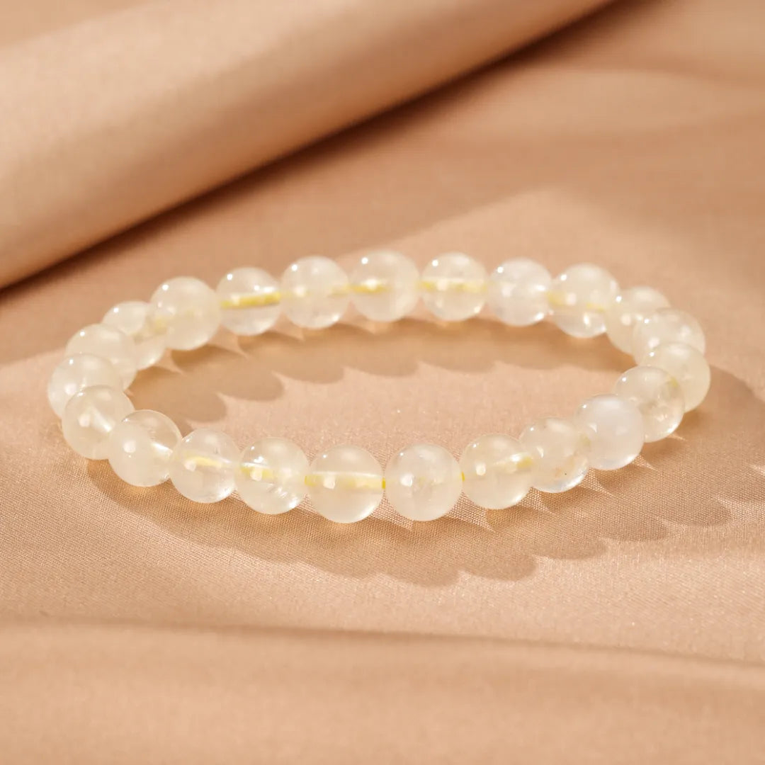 Bracelet Citrine "Lumière Intérieure" fait de perles rondes translucides de citrine pâle sur fond texturé beige.