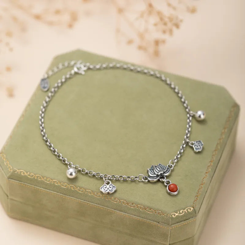 Bracelet de cheville en argent avec un pendentif lotus, une pierre d'agate rouge et des breloques nuages et billes.