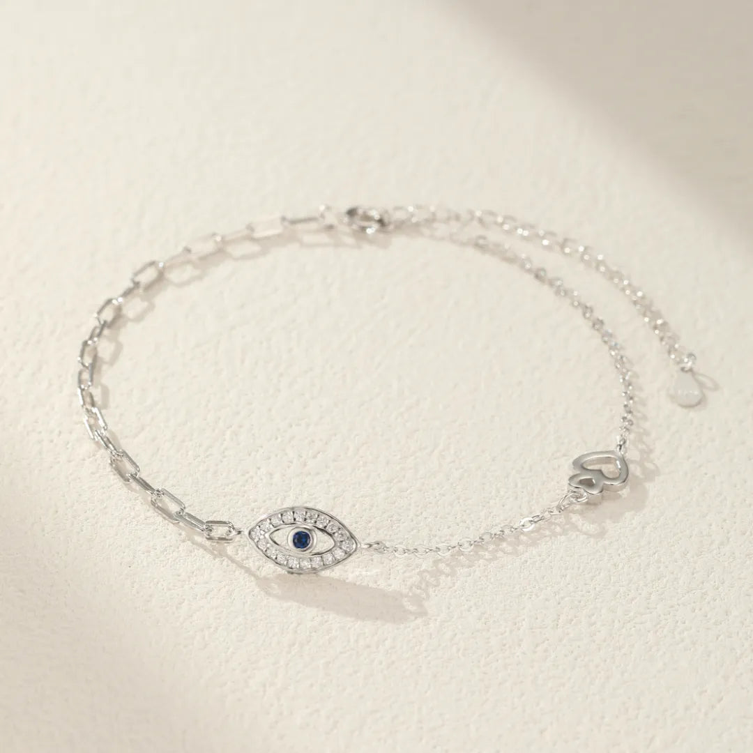 Bracelet de cheville "Cœur Protecteur" en argent 925 orné d'un œil bleu et de zirconiums scintillants, avec une breloque cœur stylisée.
