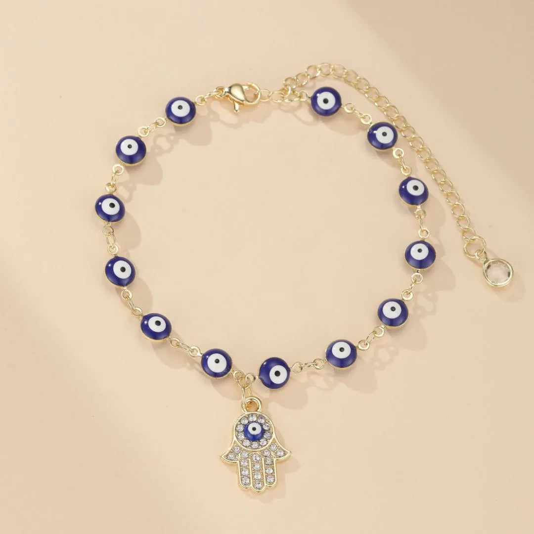 Bracelet de cheville doré serti de perles œil bleu et d'un pendentif main de Fatma orné de strass et d'un œil bleu.