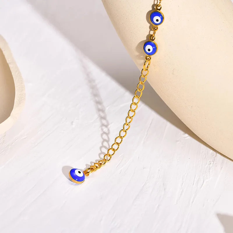 Bracelet de cheville doré avec une chaîne à maillons et des breloques œil bleu "mauvais œil" pour une protection spirituelle.