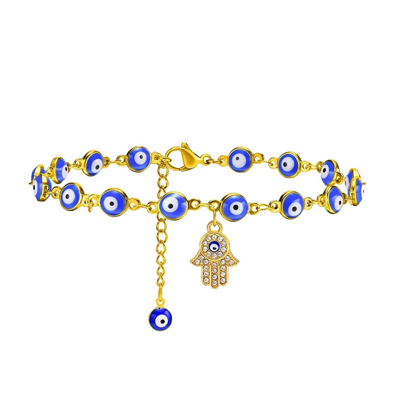 Bracelet de cheville doré avec une chaîne ornée de perles œil bleu et un pendentif main de Fatma serti de strass, et une perle œil bleu pendante.