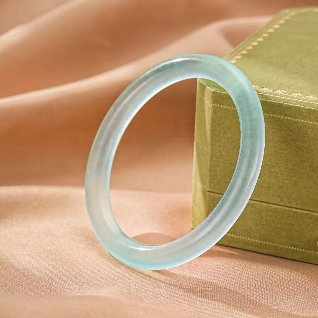 Bracelet jonc en aigue-marine "Douceur Marine" avec une finition lisse et transparente, posé sur un tissu satiné.