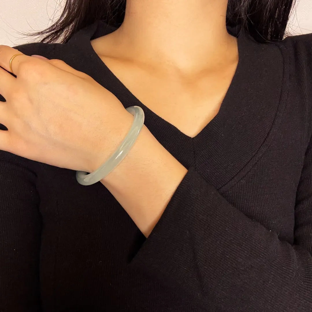 Bracelet jonc en jade Aigue Marine "Douceur Marine" porté au poignet d'une femme, avec une bague dorée à l'auriculaire.