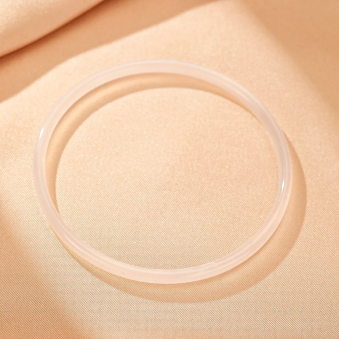 Bracelet jonc fin en calcédoine translucide "Fraîcheur Aquatique", posé sur un fond texturé de couleur crème.