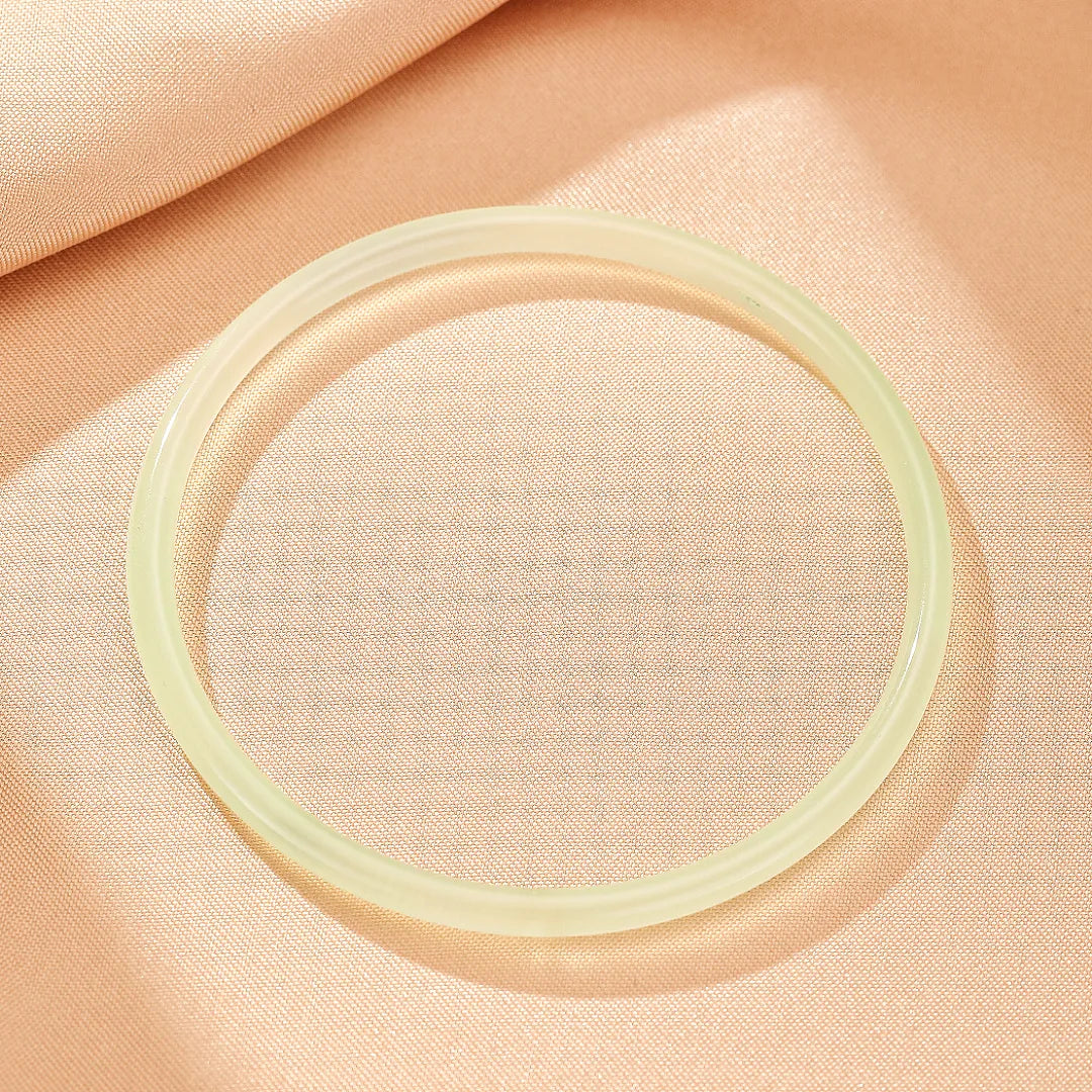 Bracelet jonc en calcédoine "Fraîcheur Aquatique" de couleur vert pâle, posé sur un tissu beige.
