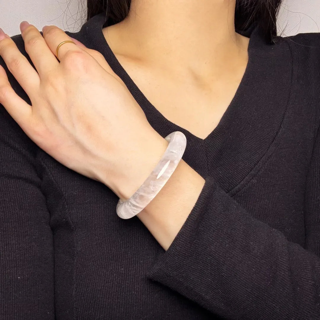 Bracelet jonc en cristal de roche translucide "Pureté Lumineuse" porté au poignet d'une femme.