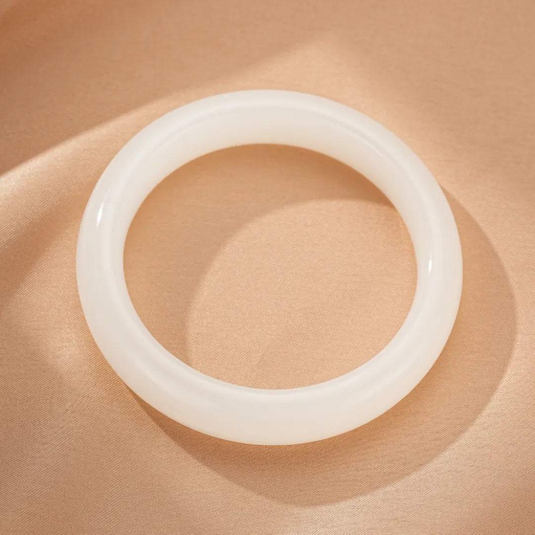 Bracelet jonc en jade blanc poli sur un fond satiné beige