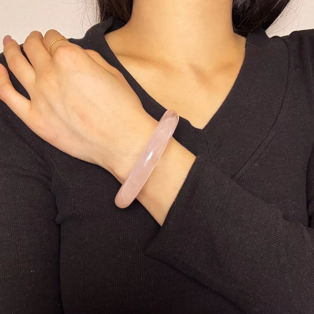Bracelet jonc en quartz rose "Amour Inconditionnel" porté au poignet d'une femme.