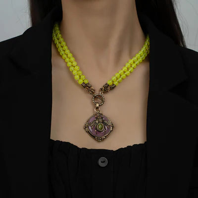 Collier "Abeille d'Or" avec pendentif carré orné d'une abeille et d'une pierre verte, monté sur deux rangs de perles d'agate jaune.