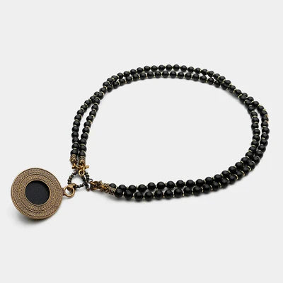 Collier double rang en agate noire avec un pendentif rond orné d'une gravure et d'une pierre noire centrale.