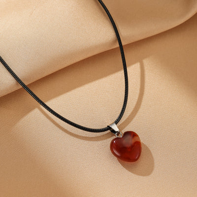 Collier "Cœur Confiant" avec un pendentif en forme de cœur en agate rouge veinée, monté sur un cordon noir.