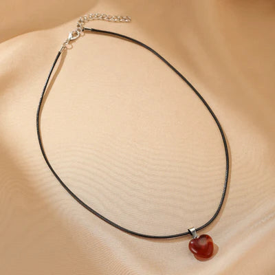 Collier avec un pendentif en forme de cœur en agate rouge, monté sur un cordon noir fin, avec une chaîne d'extension argentée.