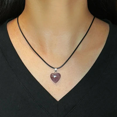 Collier "Cœur Calme" avec pendentif en améthyste en forme de cœur, porté sur un cordon noir par une personne vêtue de noir.