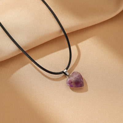 Collier avec un pendentif en améthyste taillé en forme de cœur, monté sur un cordon noir.