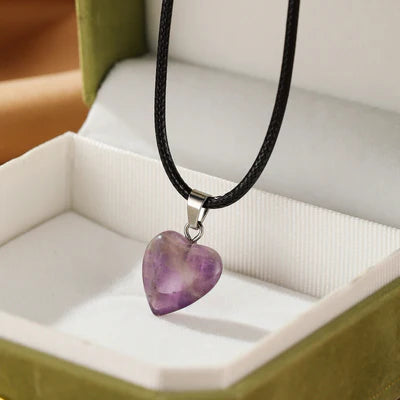 Collier "Cœur Calme" avec pendentif en améthyste en forme de cœur, sur un cordon noir, présenté dans une boîte cadeau verte.