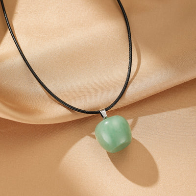 Collier Aventurine "Sérénité du Cœur" avec pendentif en forme de pomme verte sur fond satiné beige clair.