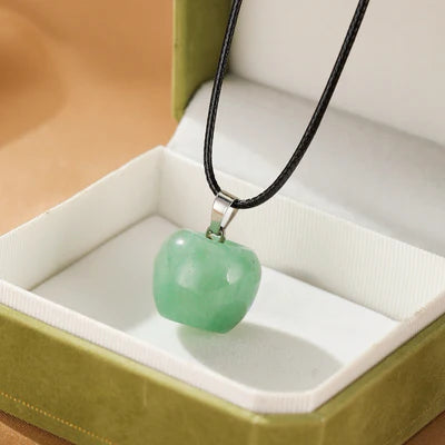 Collier Aventurine "Sérénité du Cœur" avec une pierre verte en forme de pomme sur un cordon noir, présenté dans une boîte cadeau verte.