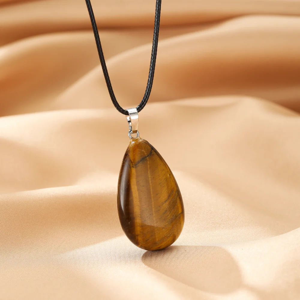 Collier avec pendentif en œil de tigre poli en forme de goutte, monté sur un cordon noir.