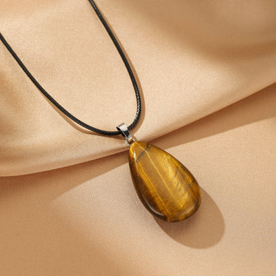 Collier "Goutte Protectrice" avec un pendentif en œil de tigre aux reflets dorés, monté sur un cordon noir.