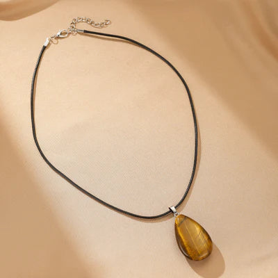 Collier "Goutte Protectrice" avec une pierre d'œil de tigre en forme de goutte d'eau sur un cordon noir.
