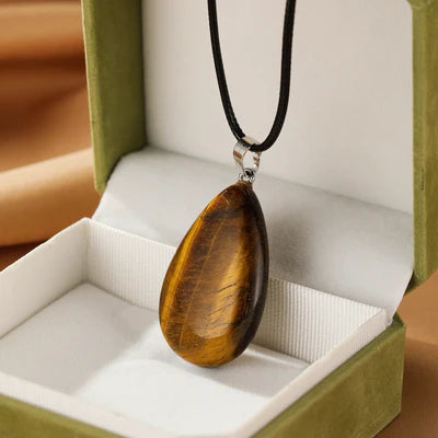 Collier pendentif goutte en œil de tigre marron et doré, présenté dans un écrin vert.
