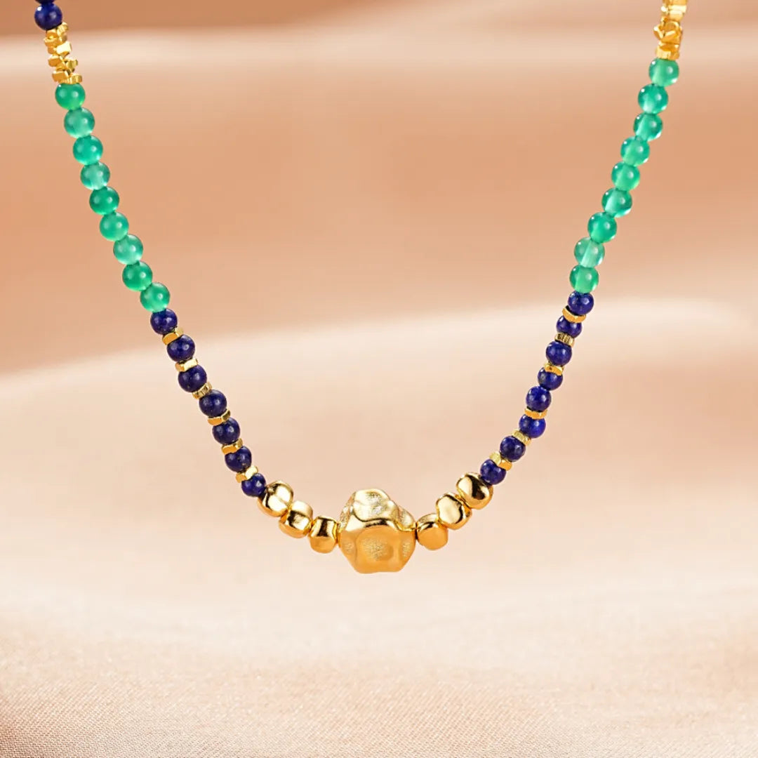 Collier avec des perles bleues de Lapis Lazuli, des perles vertes de Jade et un pendentif central doré en forme de Bouddha.
