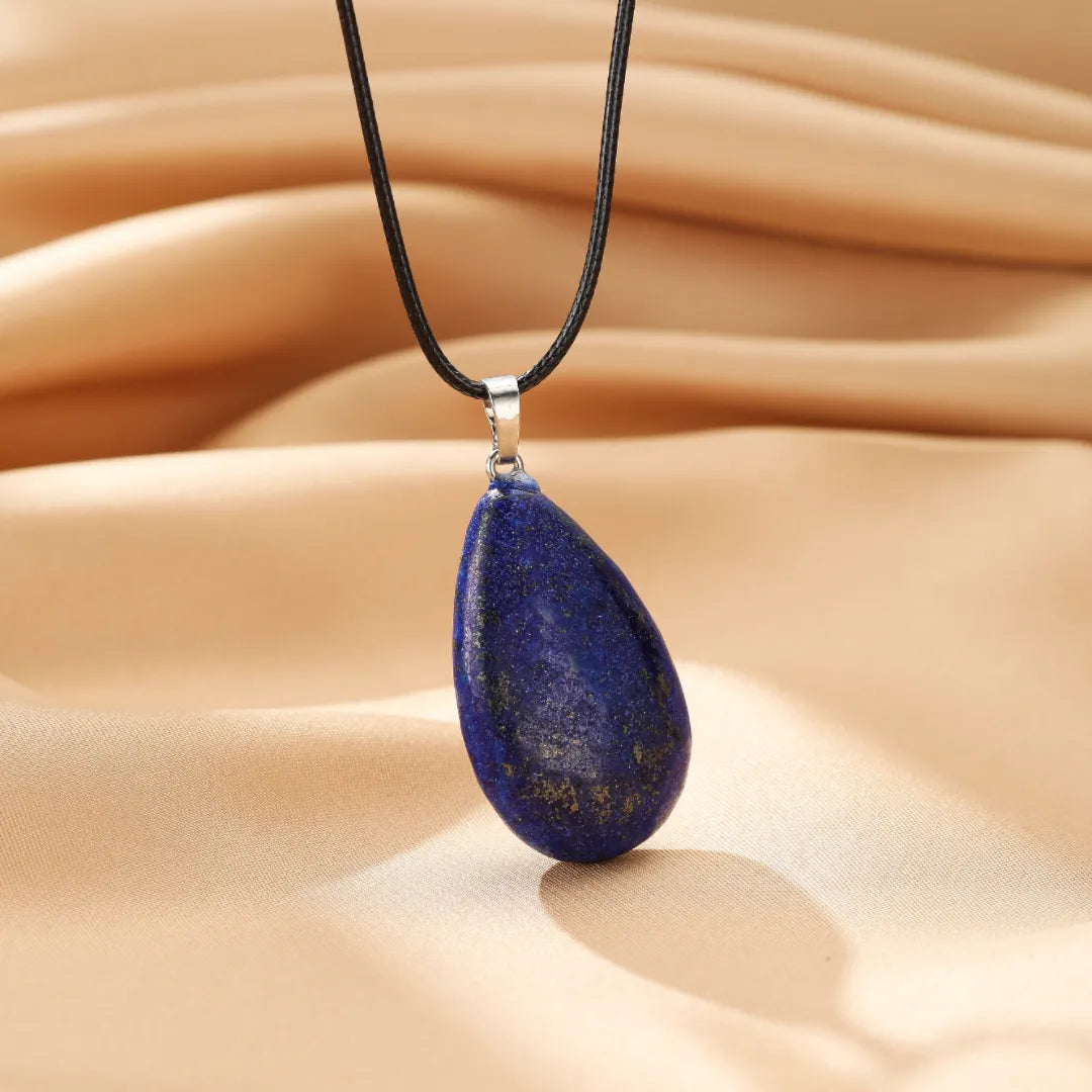 Collier avec pendentif en forme de goutte de lapis-lazuli bleu profond, suspendu à un cordon noir.