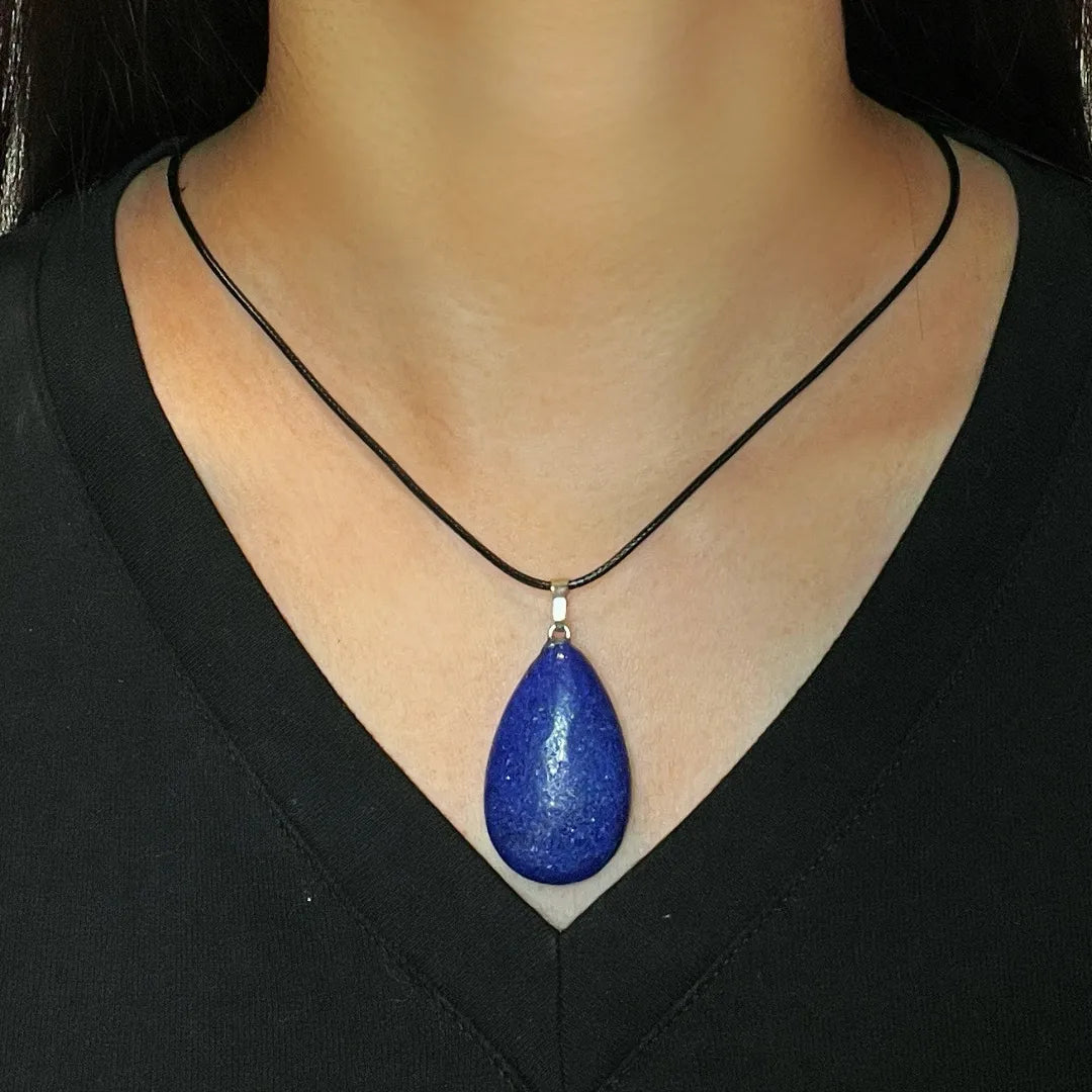 Collier avec un pendentif en forme de goutte de Lapis Lazuli bleu profond, monté sur un cordon noir et porté par une femme.