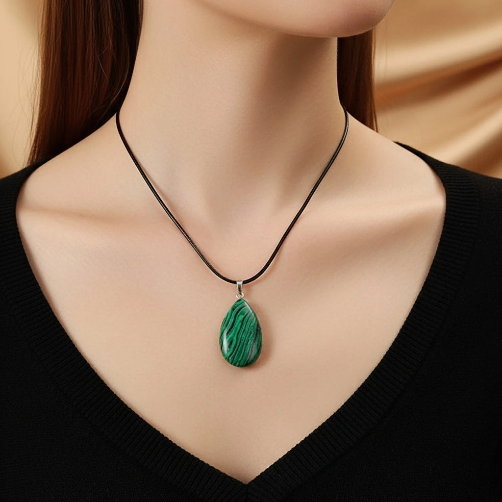 Collier ras du cou avec un pendentif en forme de goutte en malachite verte aux motifs de bandes concentriques, porté par une femme.