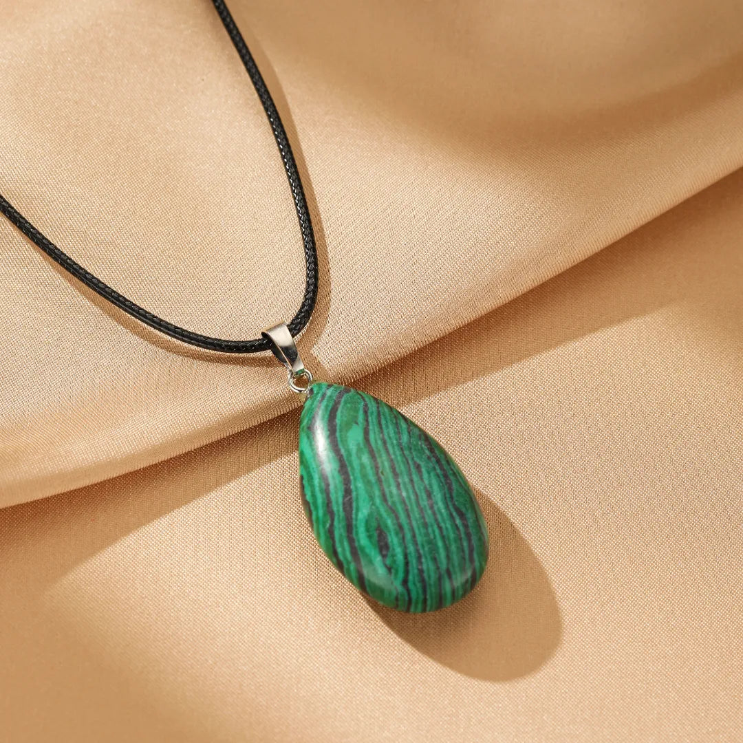 Collier avec pendentif en forme de goutte en malachite verte aux rayures noires, monté sur un cordon noir.