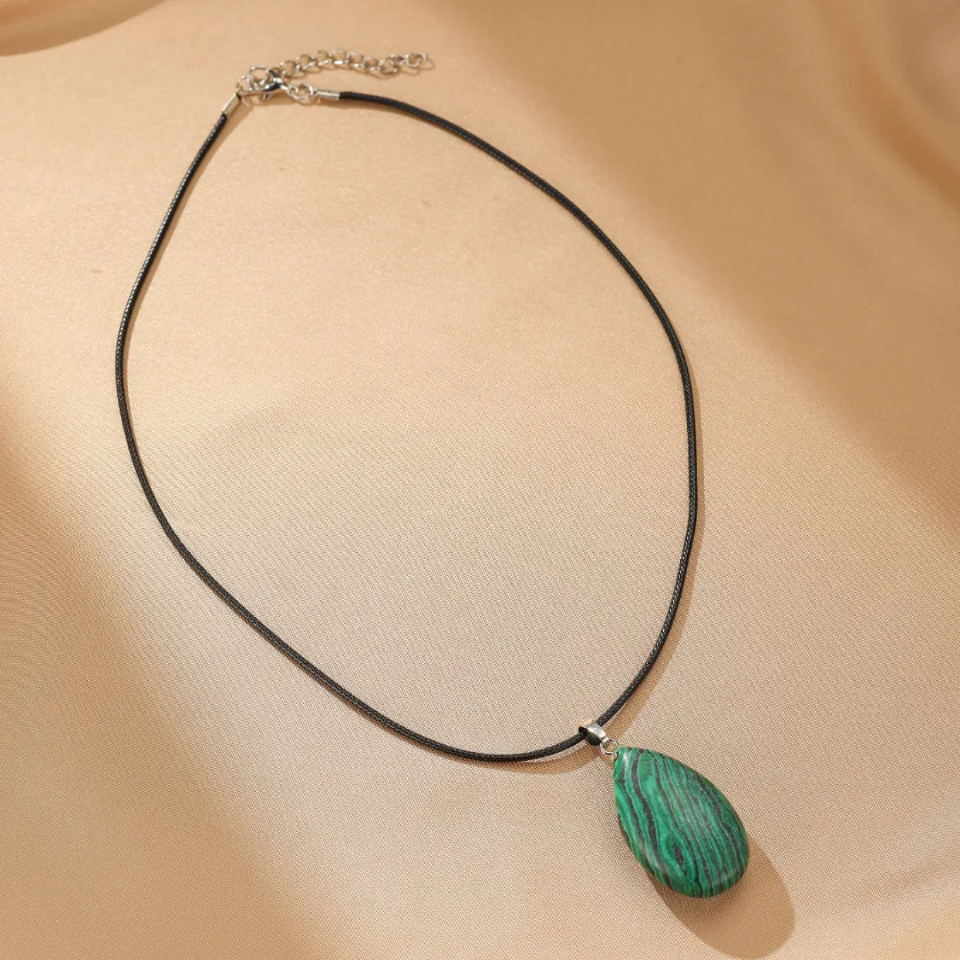 Collier "Rayons de Vitalité" avec une pierre de malachite verte en forme de goutte sur un cordon noir.